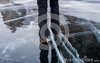 Woman walking on blue cracked ice of frozen lake Baikal. Stock Photo