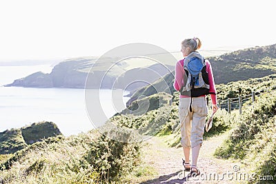 Woman walking on cliffside path Stock Photo