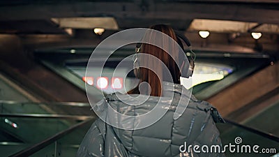 Woman walking dark subway in headphones listening music close up back view Stock Photo