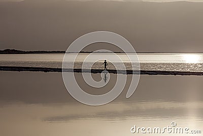 Woman walking on headland at early morning under rising sun Stock Photo