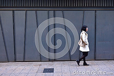 Woman walking next to an iron texture wall Stock Photo