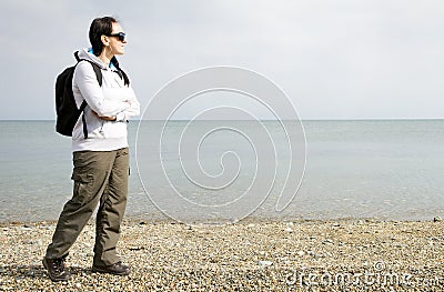 Woman walking next to the sea on pebble beach Stock Photo