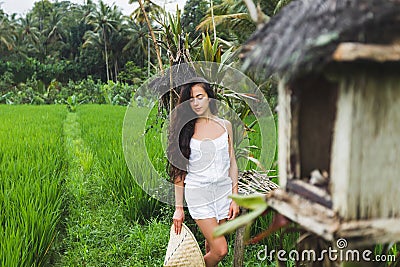 Woman walking in rice fields with traditional balinese straw hat in Ubud Stock Photo