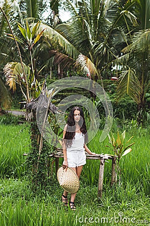 Woman walking in rice fields with traditional balinese straw hat in Ubud Stock Photo