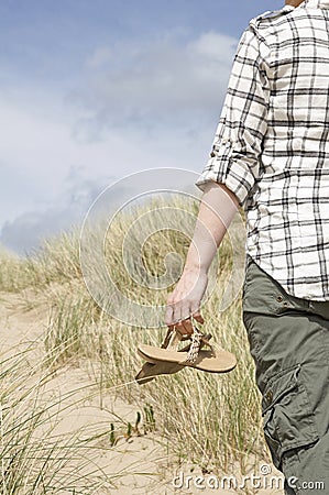 Woman walking in sand dunes holding sandals Stock Photo
