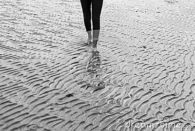 Woman walking on sandy beach leaving footprints in the beach Stock Photo