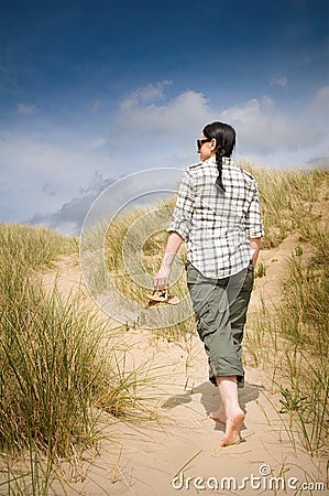 Woman walking to beach in sand dunes Stock Photo