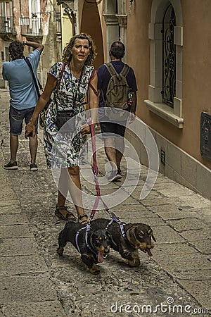 Woman walking two hound dogs in the old downtown historic district of Ortigia, Sicily Editorial Stock Photo