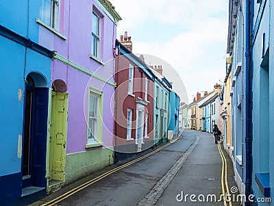 Woman walking up a narrow village street in UK Editorial Stock Photo