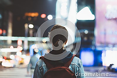 Woman walks through the night city. The view from the back. Stock Photo