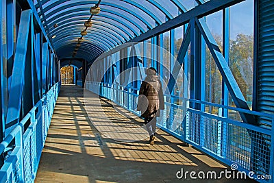 A woman walks on a overhead pedestrian bridge Editorial Stock Photo