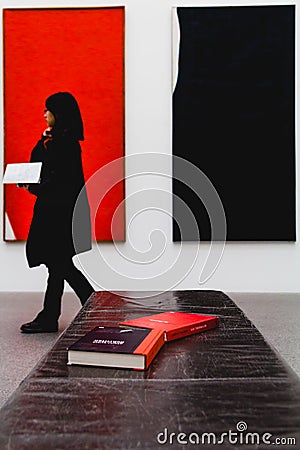 A woman walks past some books laid out with color coordinated ba Editorial Stock Photo