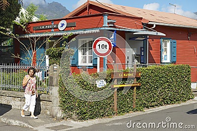 Woman walks by the street of Fond de Rond Point in Saint-Denis De La Reunion, France. Editorial Stock Photo