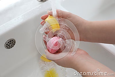 Woman washing baby bottle nipples under stream of water, above view Stock Photo
