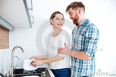 Woman washing dishes and man wants to help her Stock Photo