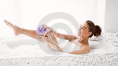 Woman Washing Leg With Sponge In Bath With Foam Stock Photo