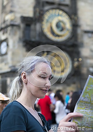 Woman watches the map of the city on background of historical medieval astronomical Clock on the Old Town Hall in Prague, Czech Re Stock Photo
