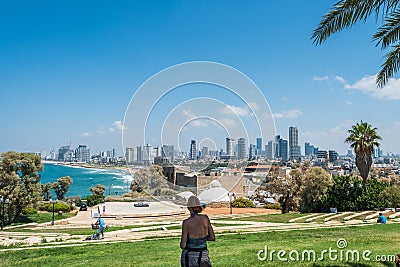 A woman watching cityscape of Tel Aviv from Abrasha Park across the bay in Jaffa, with palm trees and skylines Editorial Stock Photo