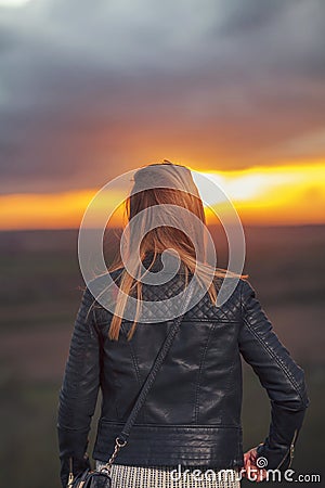 Young Woman watching sun at sunset alone Stock Photo