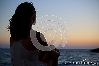 Woman watching the sunset by the sea Stock Photo