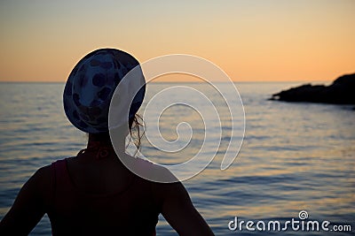 Woman watching the sunset by the sea Stock Photo