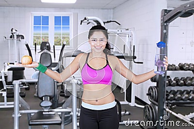 Woman with water bottle and apple on gymnasium Stock Photo