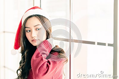 Woman wear Santa hat standing near the window Stock Photo