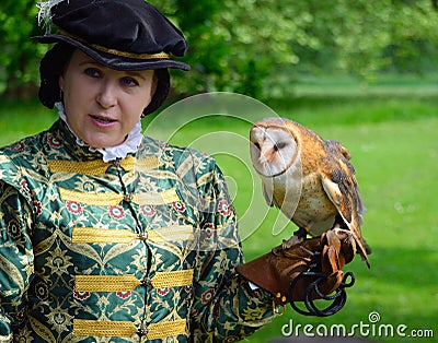 Woman wearing Elizabethan costume with Barn Owl on Gloved hand. Editorial Stock Photo