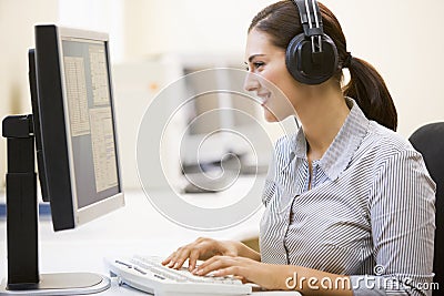 Woman wearing headphones in computer room typing Stock Photo