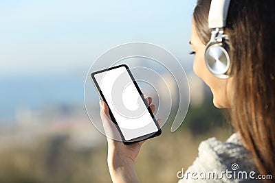 Woman wearing headphones showing blank phone screen Stock Photo
