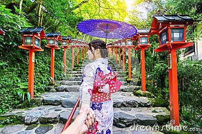 Woman wearing japanese traditional kimono holding man`s hand and leading him to Kifune shrine, Kyoto in Japan Stock Photo