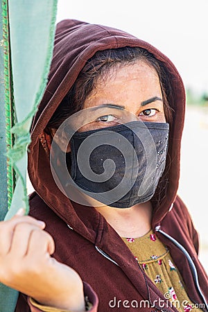 Woman wearing a mask, at a field where pears are being prepared and dried in the sun Editorial Stock Photo