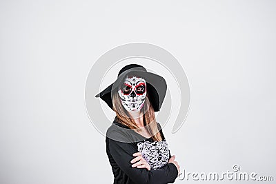 woman wearing mexican face mask during halloween celebration. skeleton costume and black stylish hat. woman with arms crossed. Stock Photo