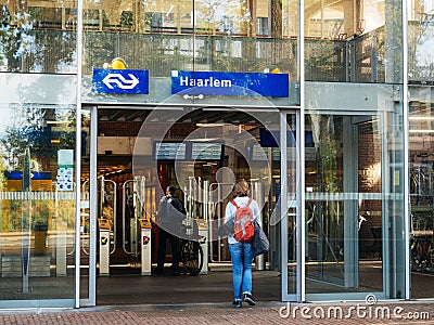 Woman wearing red backpack entering through door train sttion Editorial Stock Photo