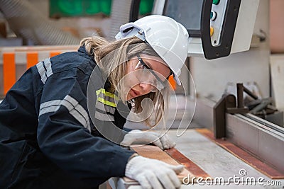 woman wearing safety uniform and hard hat working quality inspection of wood products at workshop manufacturing wooden. female Stock Photo
