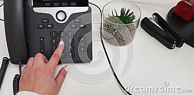 Woman wearing white nail polish dials a number with her left hand Stock Photo