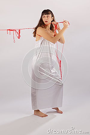 Woman white silk nightie pulling weg red thread on white background Stock Photo