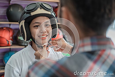 Woman wears a helmet with the help of a shop assistant when attaching the strap buckle Stock Photo