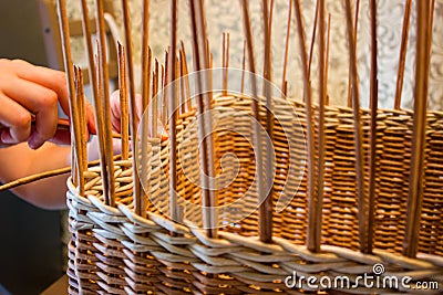 A woman weaves a basket from a paper vine. Stock Photo