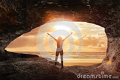 Woman welcomes the sunrise in a cave Stock Photo