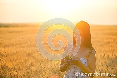 Woman with a wheat bouguet in wheat field at sunset Stock Photo