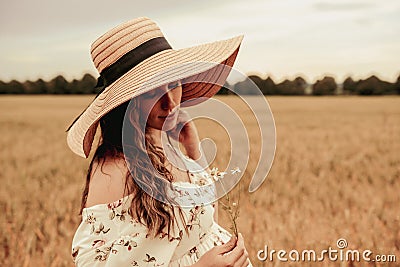 Woman wheat field nature. Happy young woman in sun hat in summer wheat field at sunset. Copy space, sunset, flare light Stock Photo