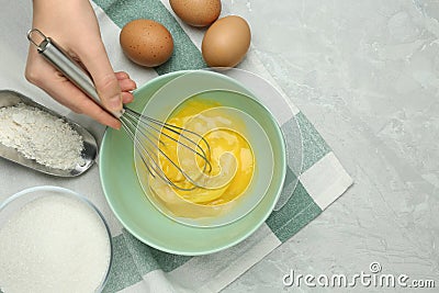 Woman whisking eggs in bowl at grey table, top view. Space for text Stock Photo