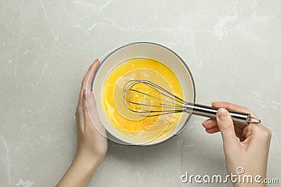 Woman whisking eggs in bowl at grey table, top view Stock Photo