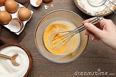 Woman whisking eggs at wooden table, top view Stock Photo