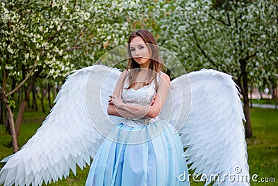 woman in a white corset and a blue puffy dress with large white angel wings behind her back Stock Photo
