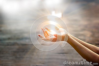 Woman with white cross in hands praying on sunlight Stock Photo