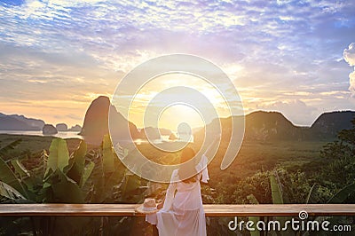 Woman with the white dress sit and see the mountain in early morning at Samet Nangshe viewpoint in Andaman sea on morning cloudy Stock Photo