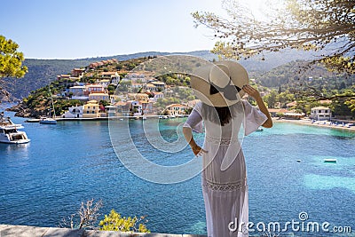 A woman with white hat enjoys the view to the village of Assos on the island of Kefalonia, Greece Stock Photo