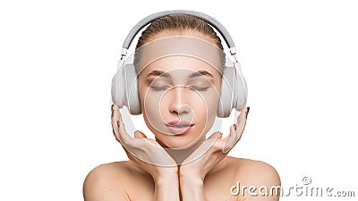 Woman in white headphones on white background listens to music with closed eyes. Stock Photo